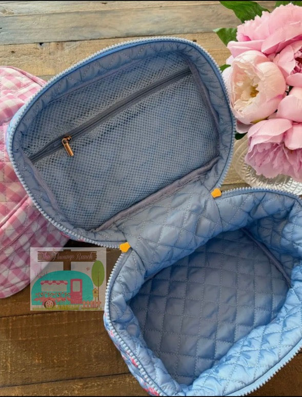 Blue quilted bag with floral design on a wooden surface with pink flowers.