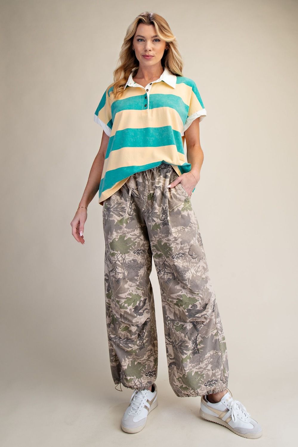 Woman wearing a striped shirt and camouflage pants on a beige background