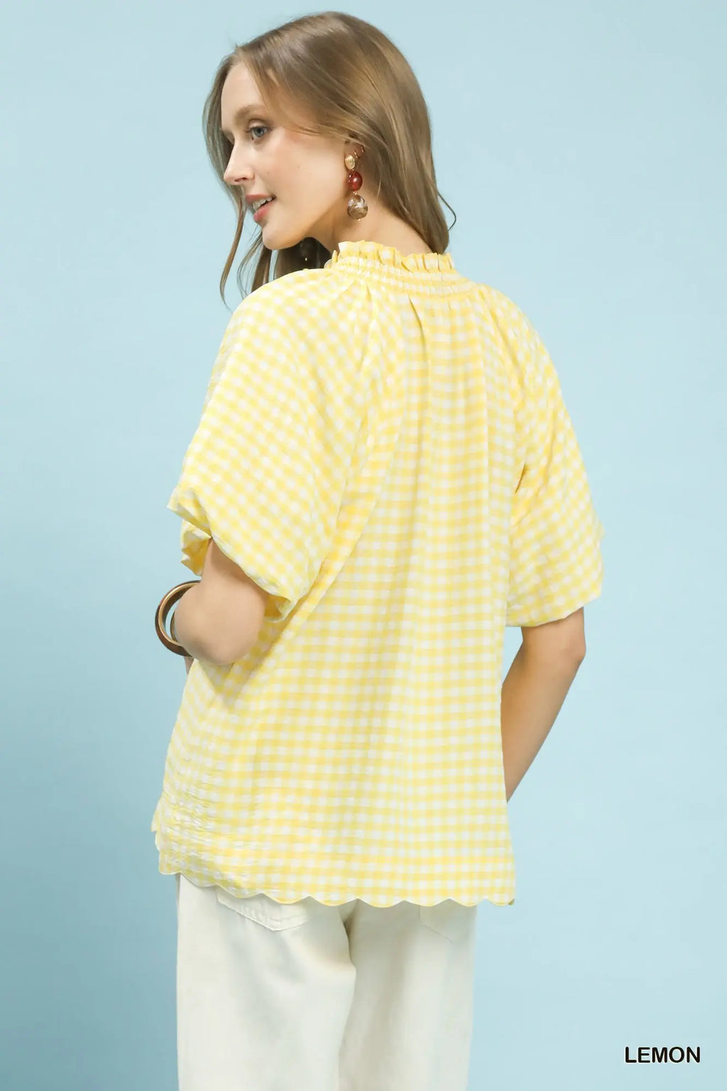 Woman wearing a yellow checkered shirt against a light blue background