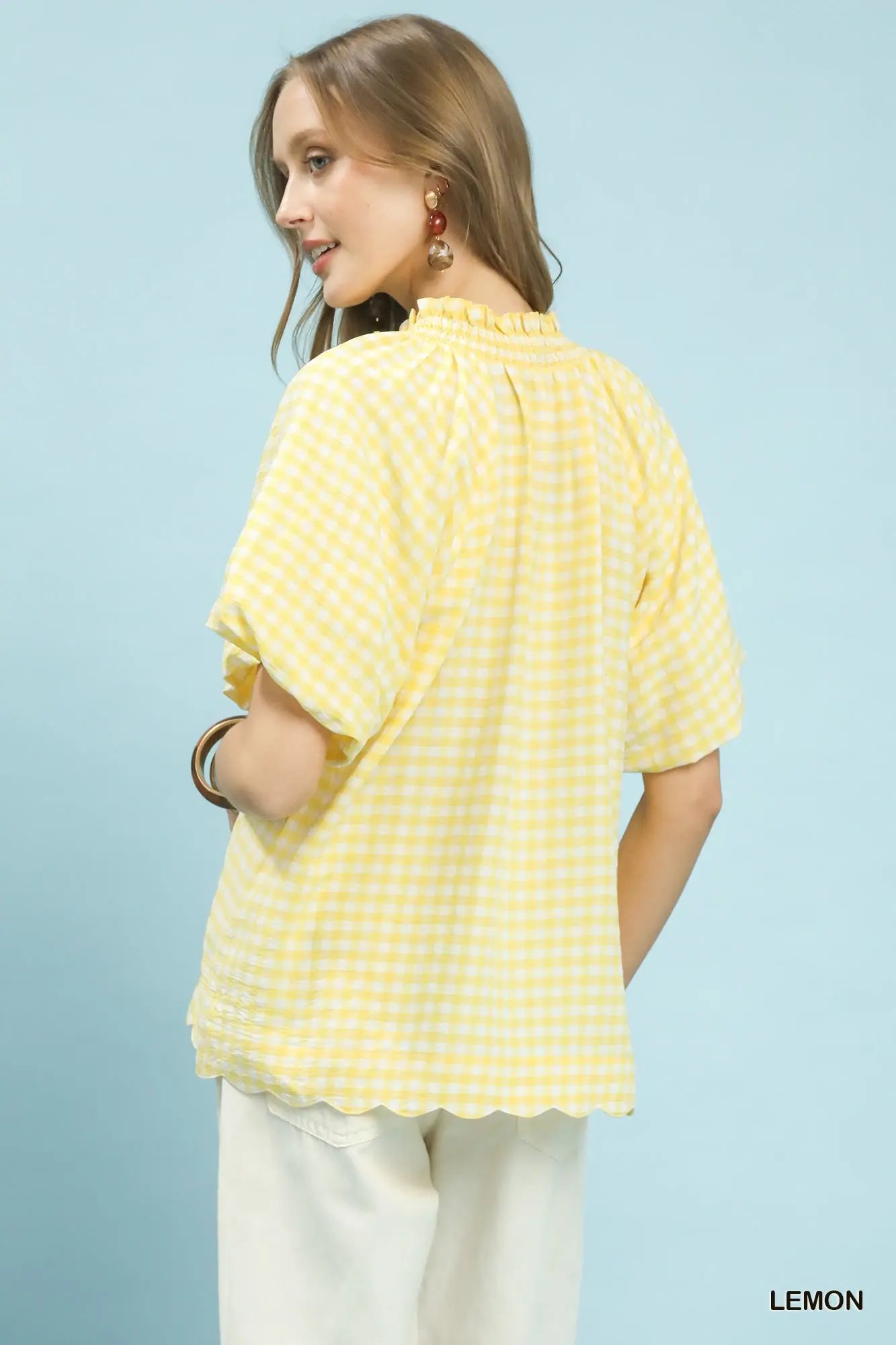 Woman wearing a yellow checkered shirt against a light blue background
