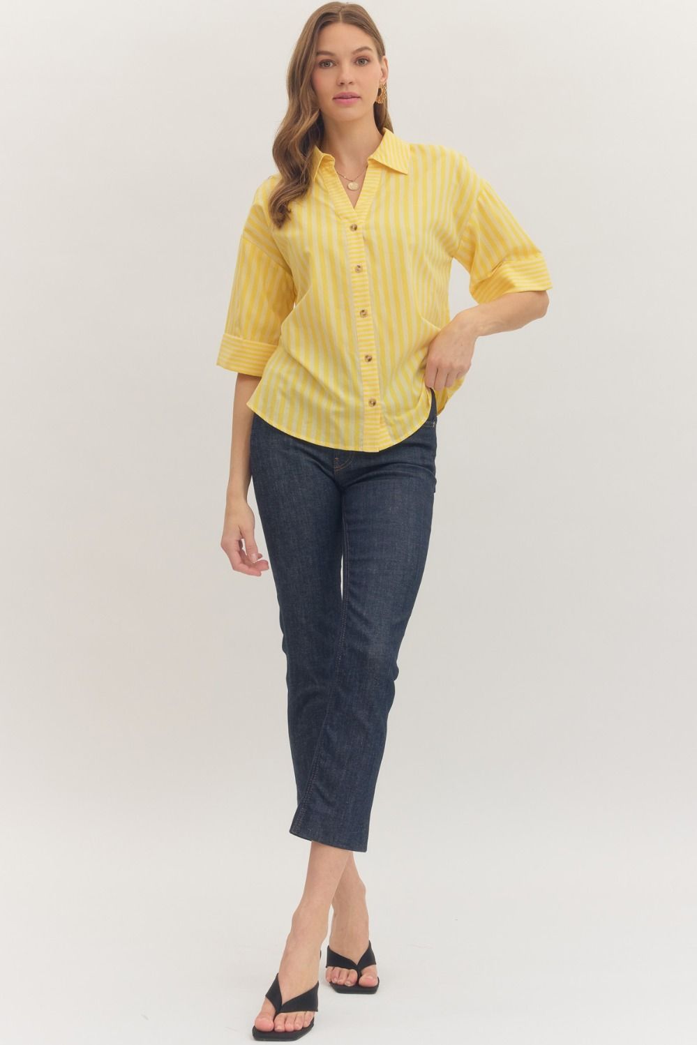 Woman wearing a yellow striped shirt and blue jeans on a white background