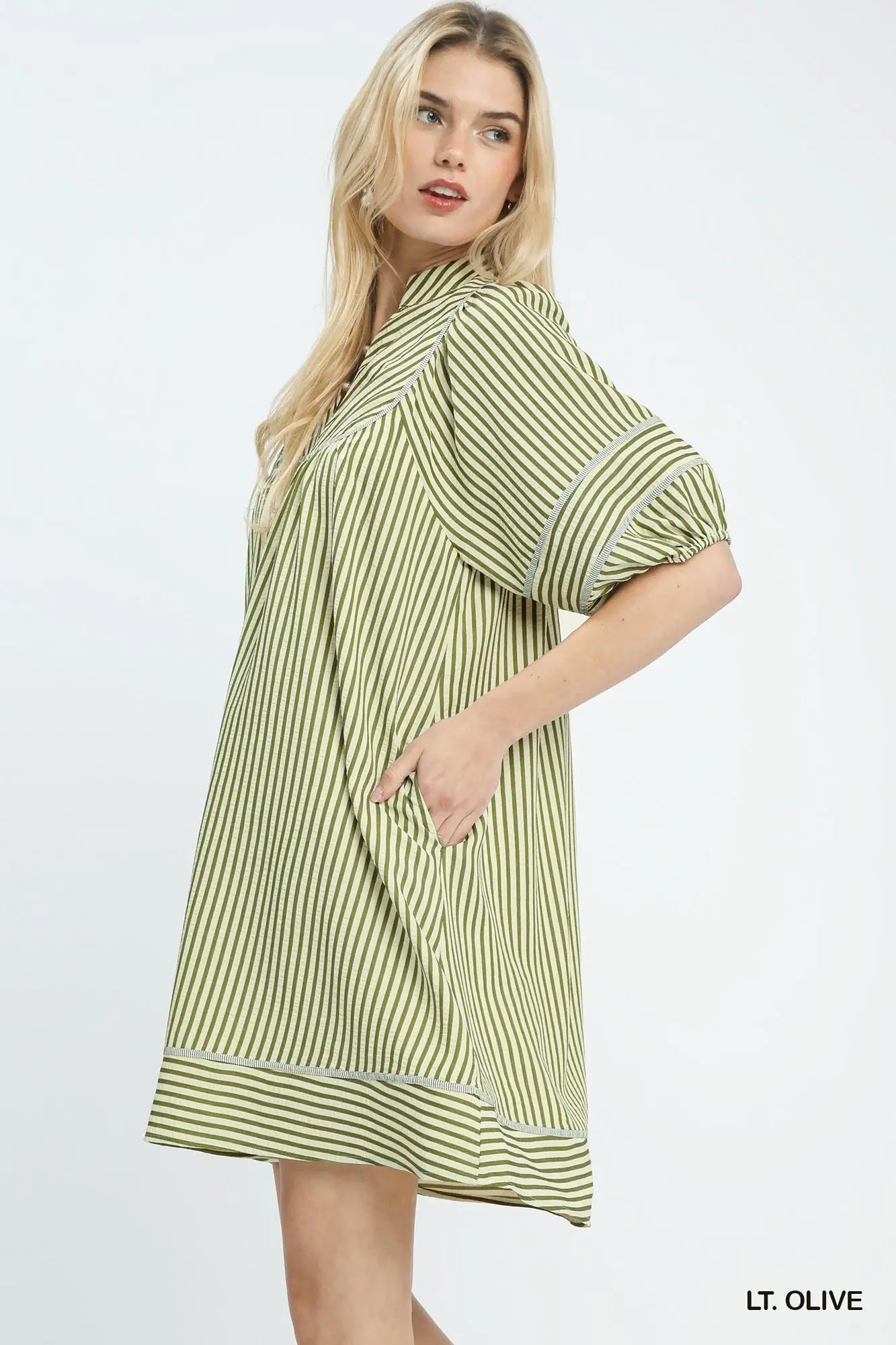 Woman wearing a light olive striped dress on a white background