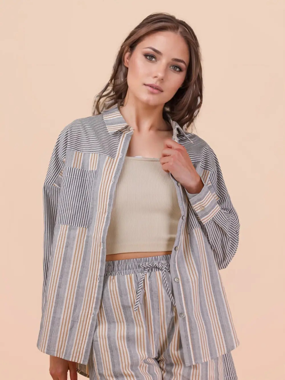 Woman wearing a striped shirt and pants set against a beige background