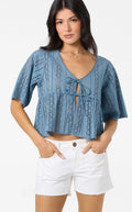 Woman wearing a blue crochet top and white shorts on a white background