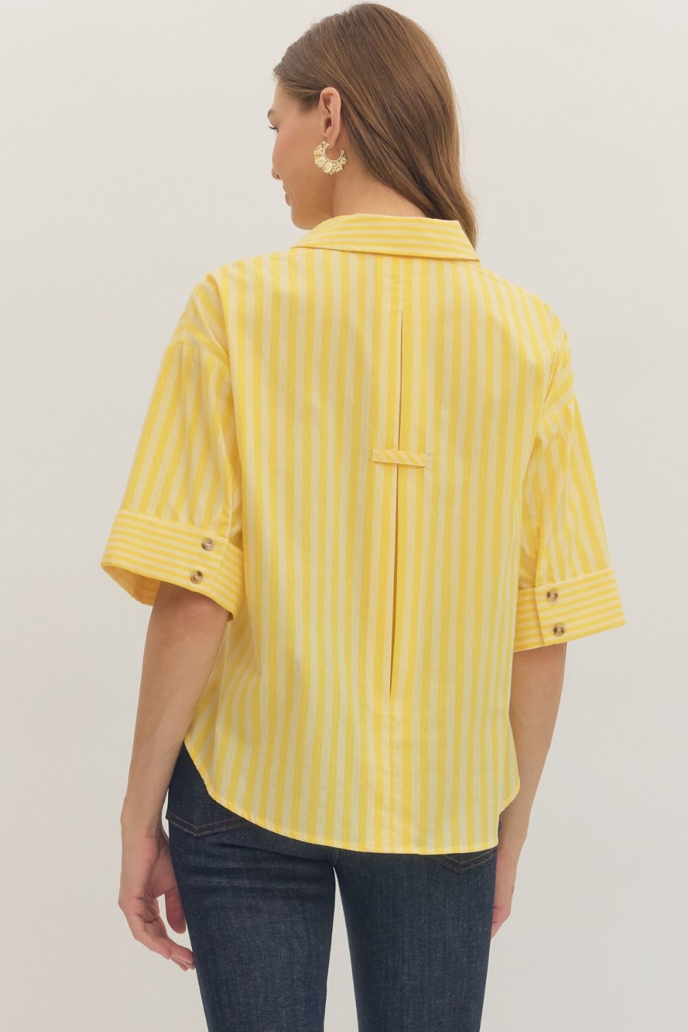 Woman wearing a yellow striped shirt against a plain background