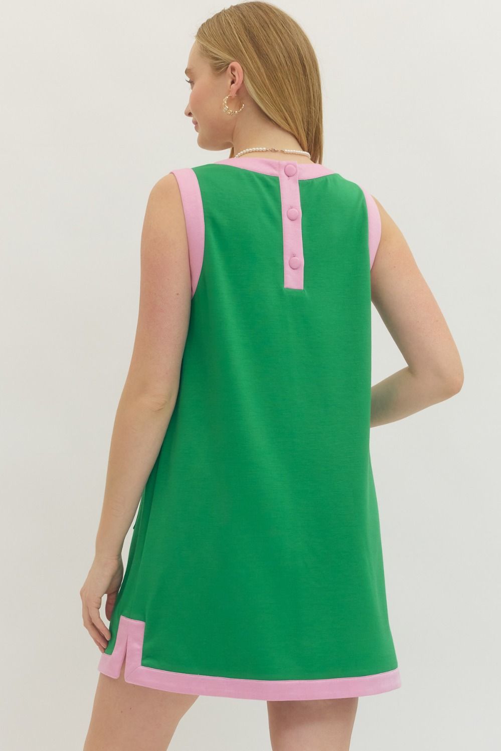 Green dress with pink accents worn by a model on a plain background