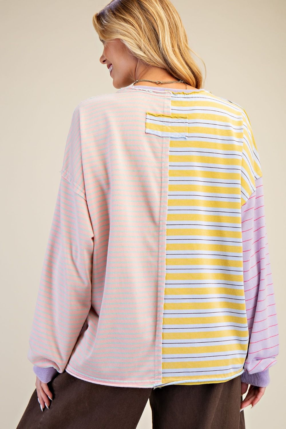 Woman wearing a pink and yellow striped shirt with a beige background