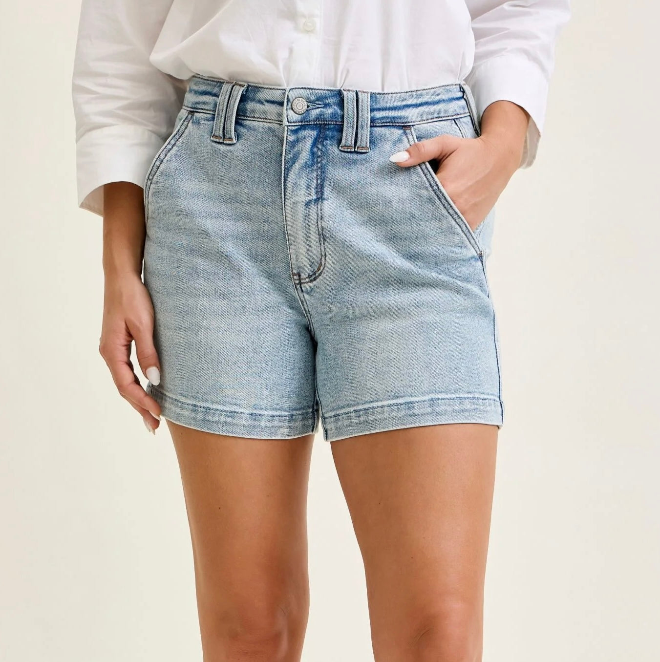 Person wearing light blue denim shorts on a plain background