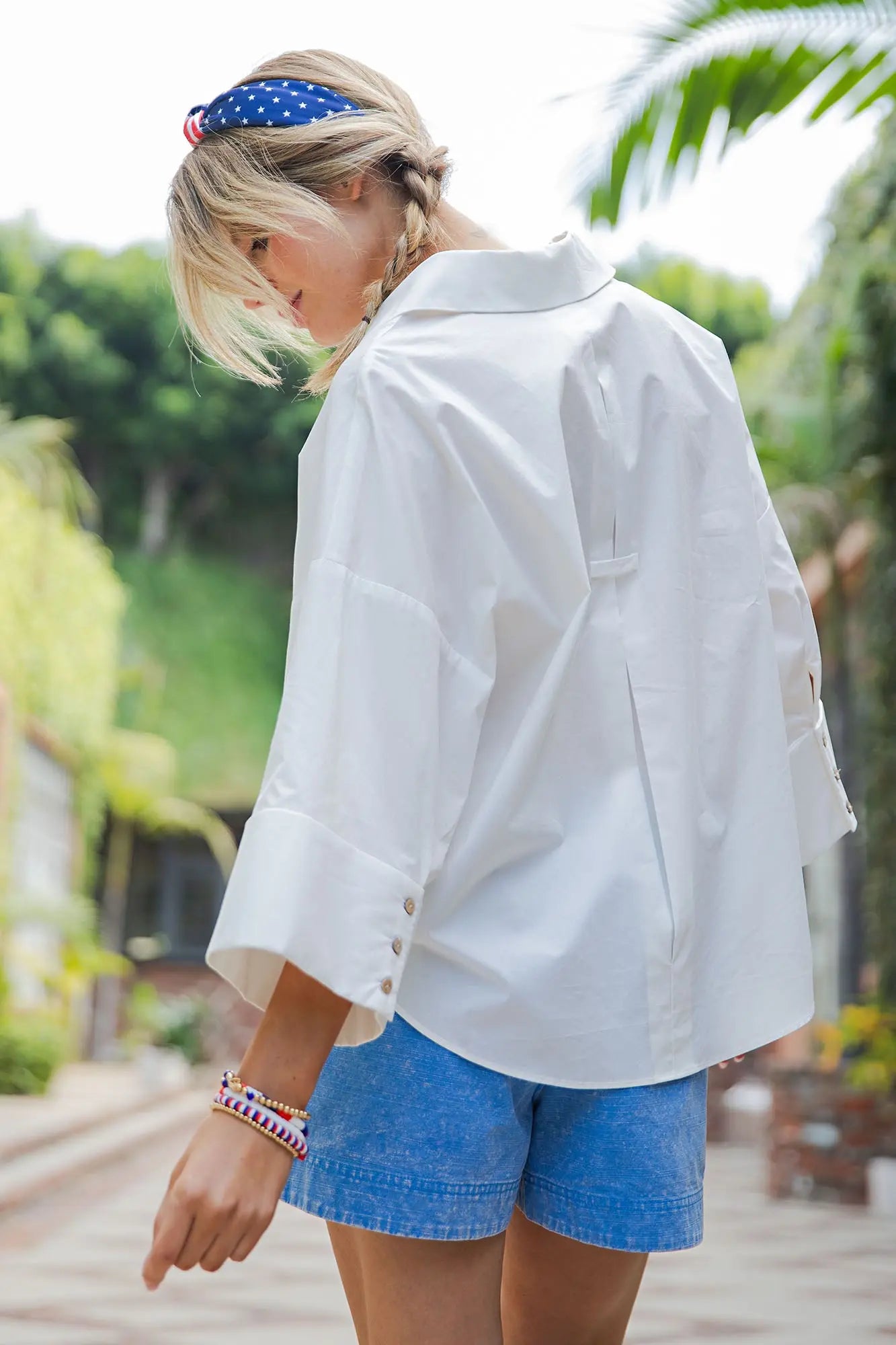 Person wearing a white shirt and blue shorts with a blurred outdoor background
