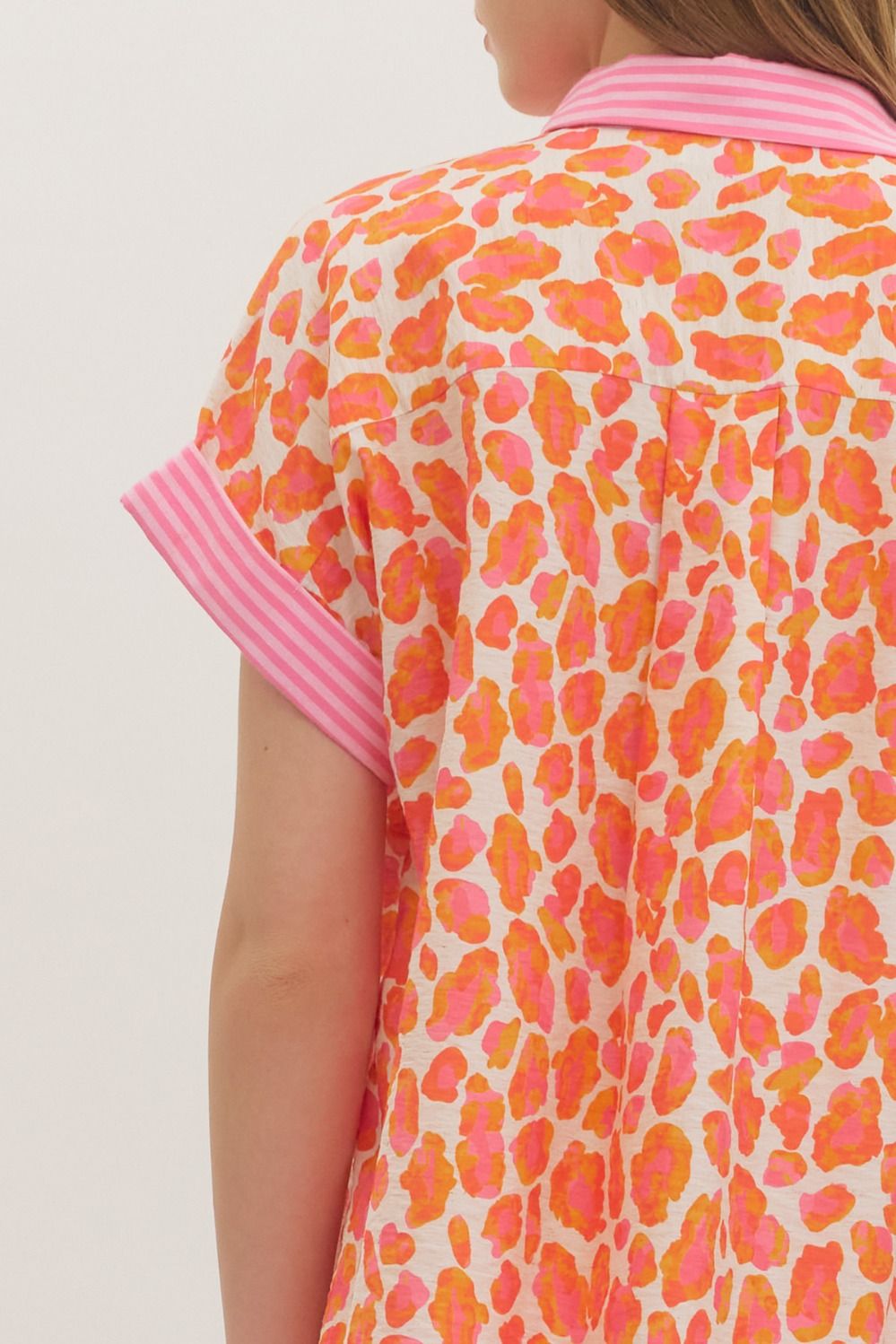 Close-up of a colorful patterned shirt with pink accents on a plain background