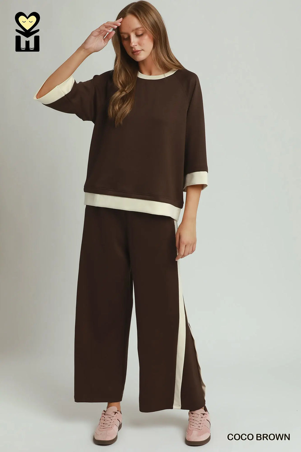 Woman wearing a brown outfit with white accents on a plain background