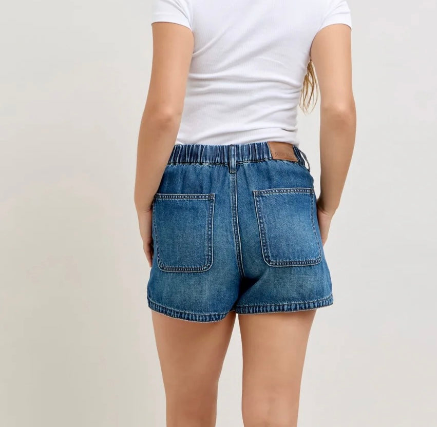 Person wearing blue denim shorts and a white t-shirt on a plain background