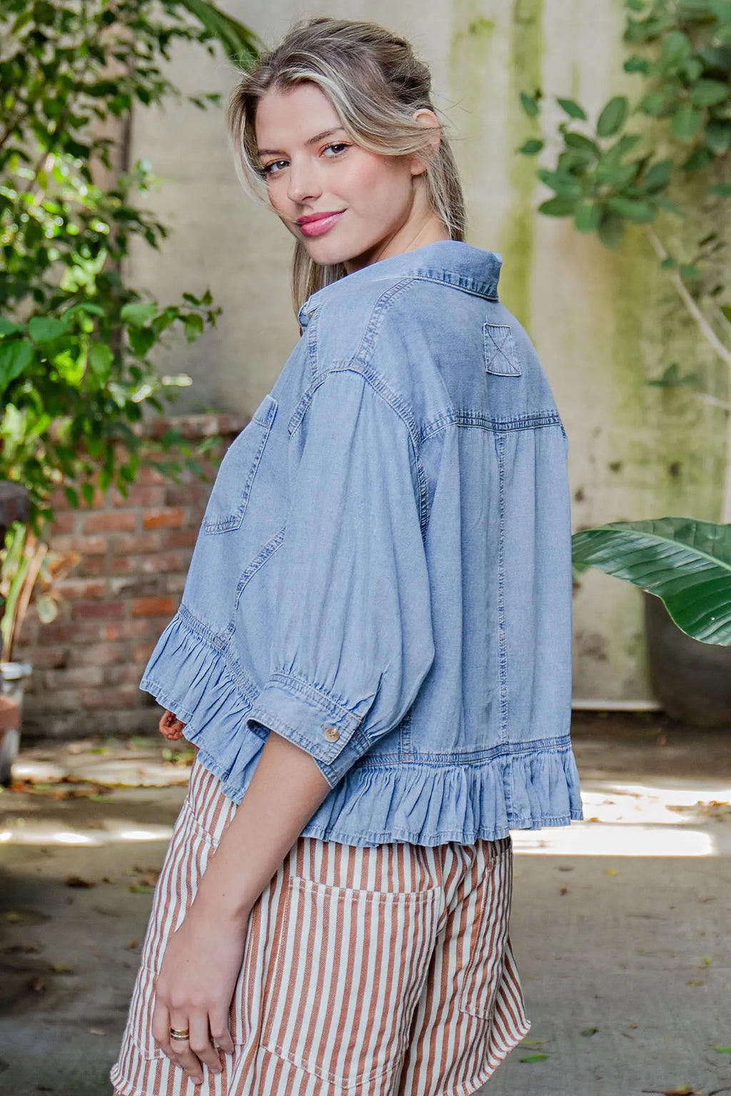 Woman wearing a blue denim jacket with a blurred natural background