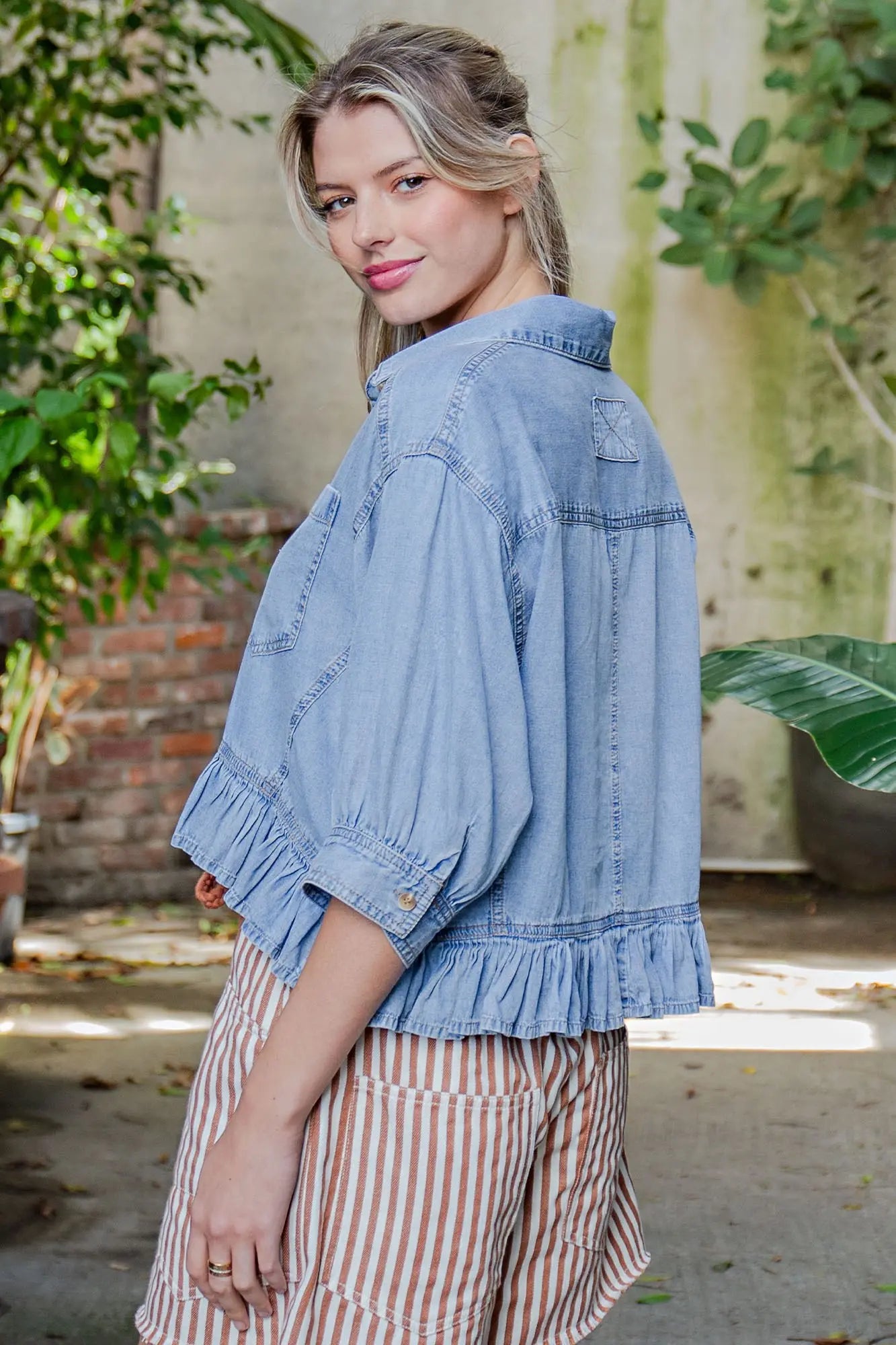 Woman wearing a blue denim jacket with a blurred natural background