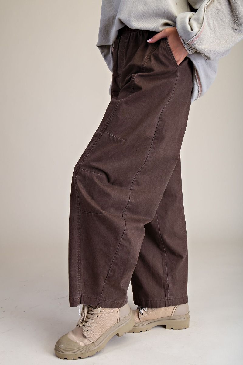 Person wearing brown wide-leg pants and beige boots on a plain background