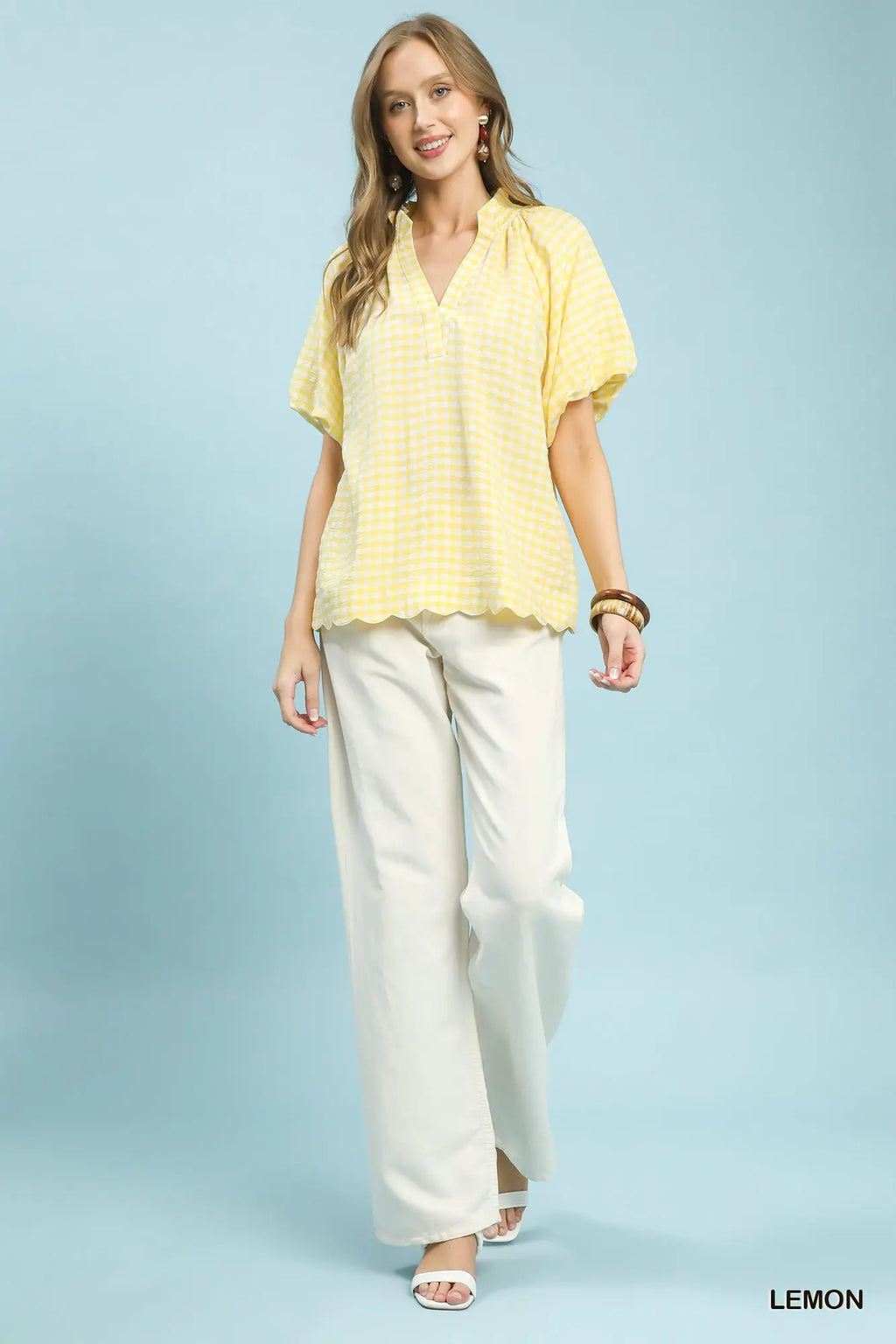 Woman wearing a yellow blouse and white pants on a light blue background