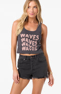Woman wearing a tank top with 'WAVES WAVES WAVES WAVES' text and black shorts on a white background