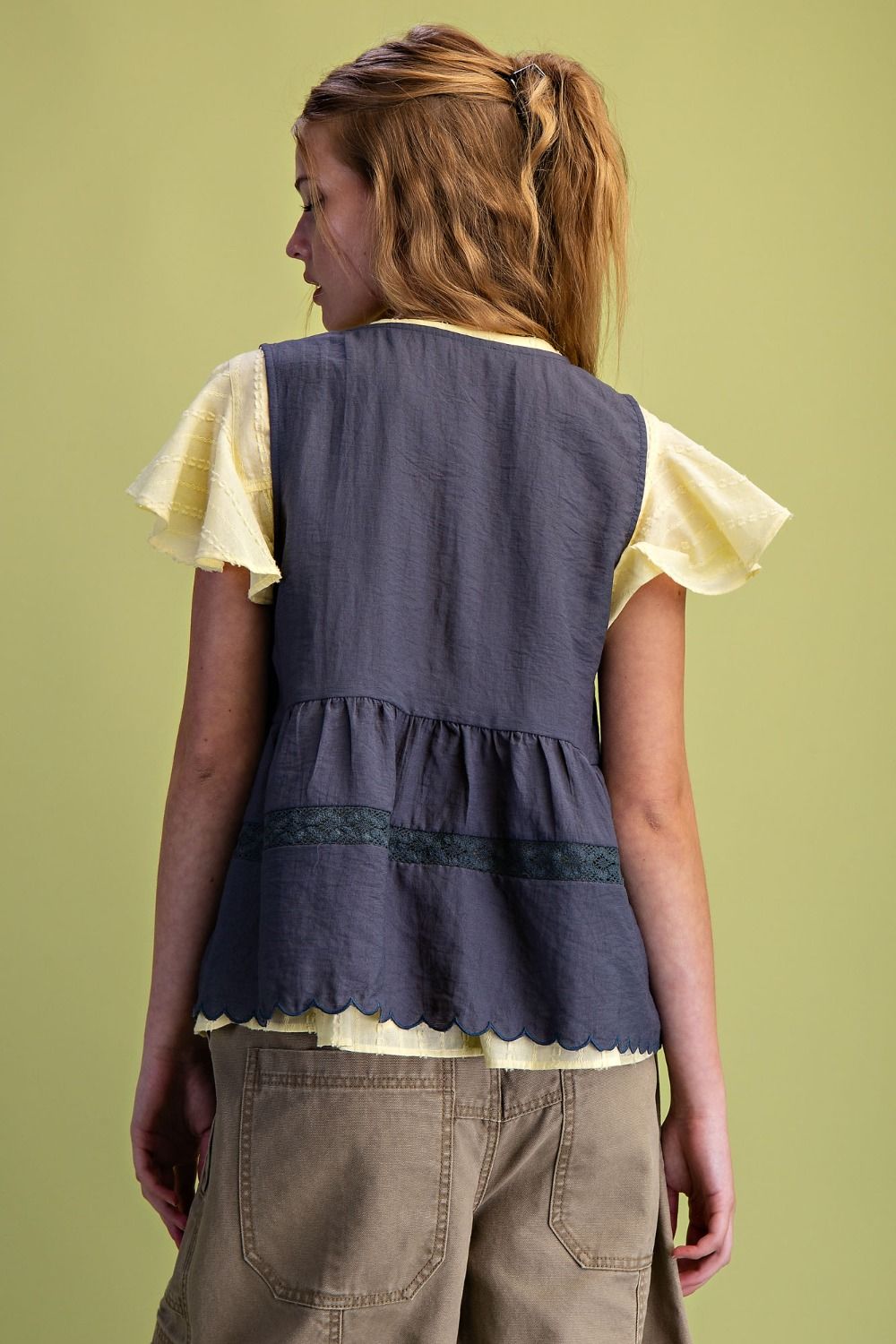Woman wearing a layered top with a plain background