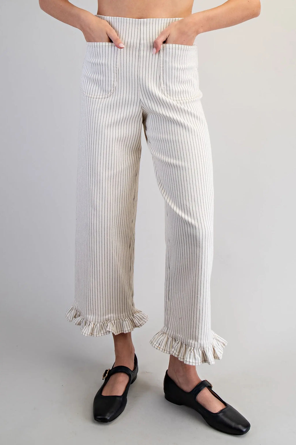 Person wearing white ruffled pants with a plain background