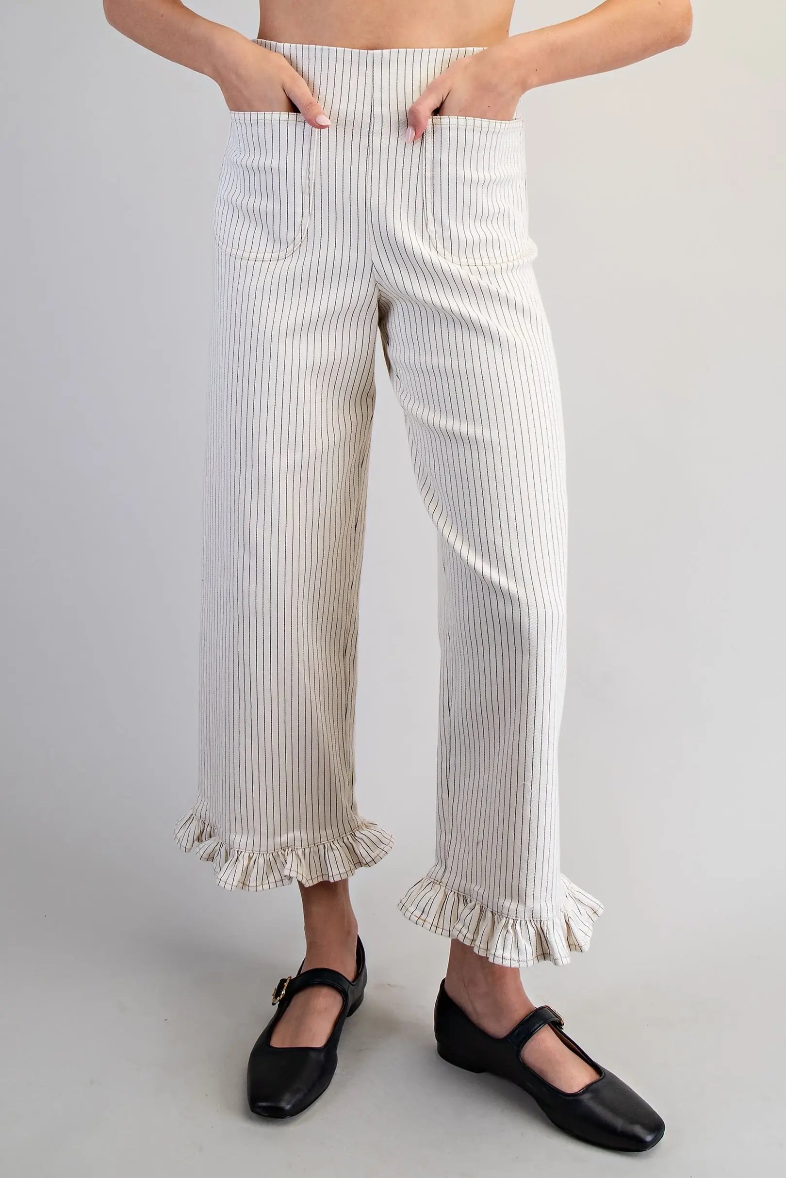 Person wearing white ruffled pants with a plain background