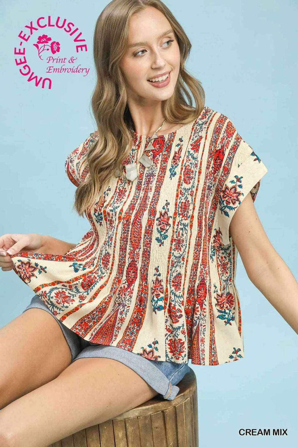 Woman wearing a floral blouse with a blue background, featuring 'Mabee Exclusive' branding.