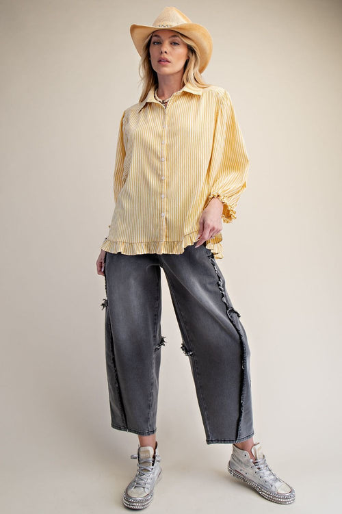 Person wearing a yellow striped shirt, gray pants, and a beige cowboy hat on a plain background