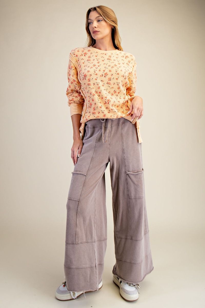 Woman wearing a patterned top and wide-leg pants on a beige background