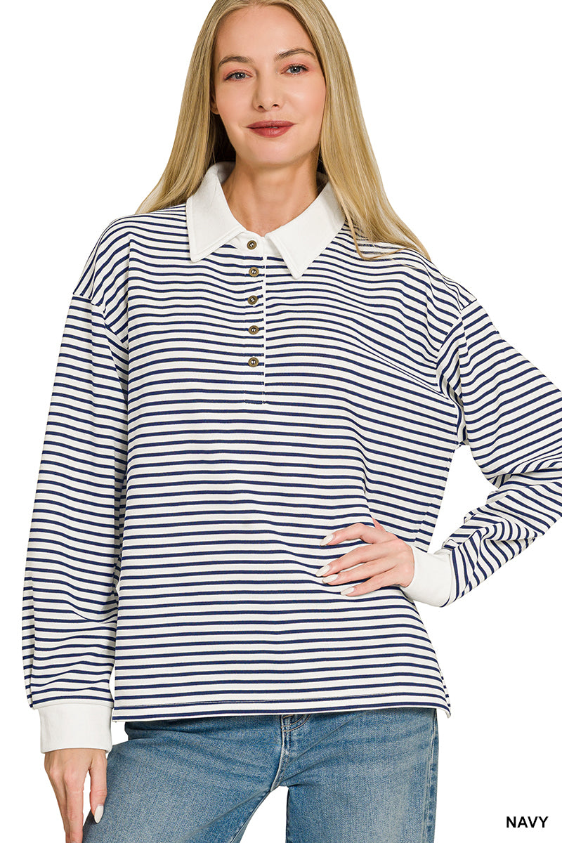 A woman modeling a long-sleeve polo shirt with navy and white horizontal stripes, featuring a solid white collar and cuffs, paired with blue jeans against a plain white background.