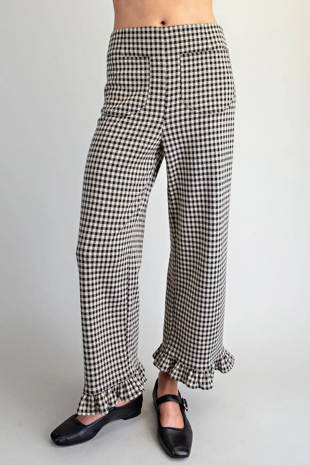 Black and white gingham wide-leg pants with ruffled hems, shown on a model wearing black Mary Jane shoes against a light gray background.
