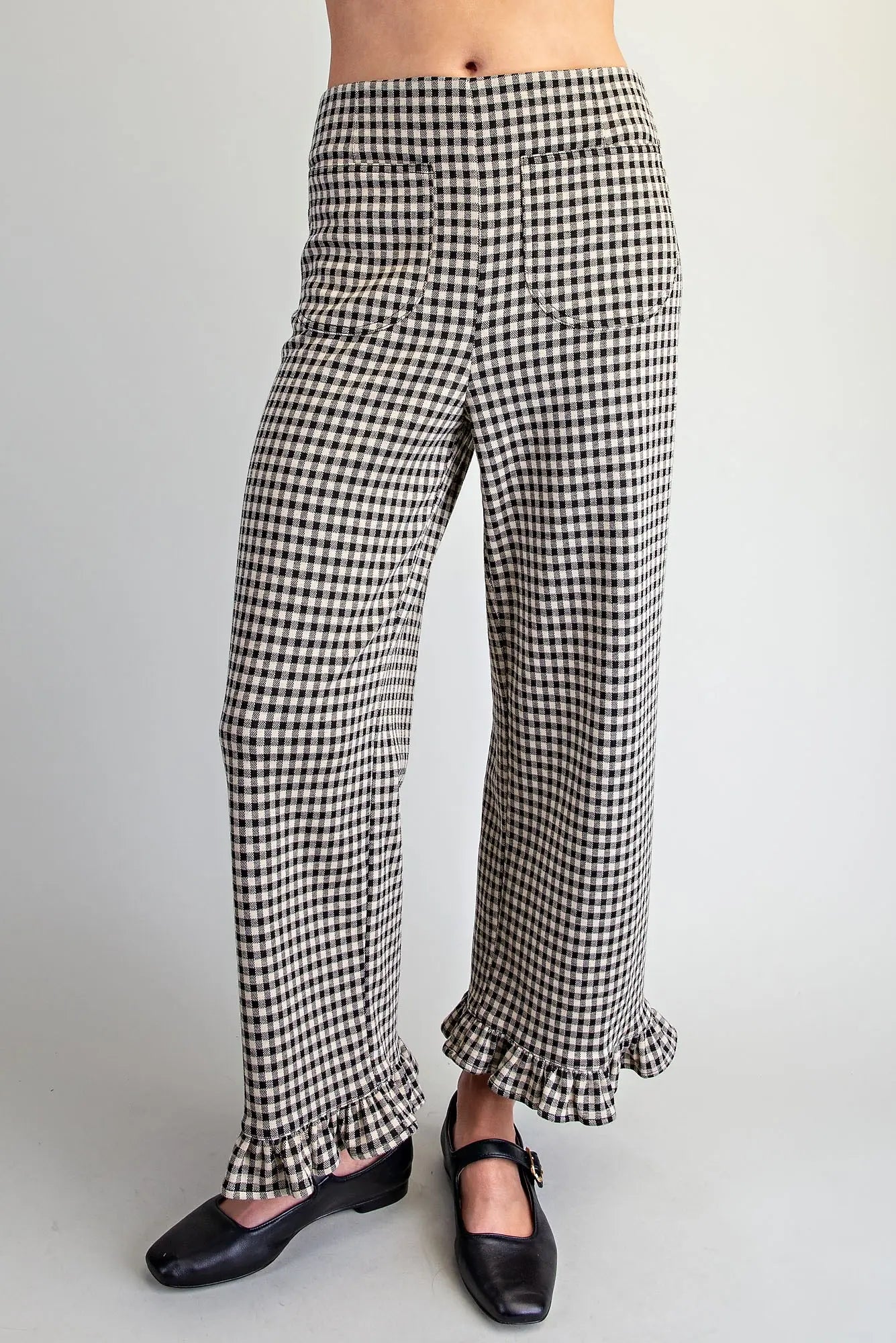 Black and white gingham wide-leg pants with ruffled hems, shown on a model wearing black Mary Jane shoes against a light gray background.