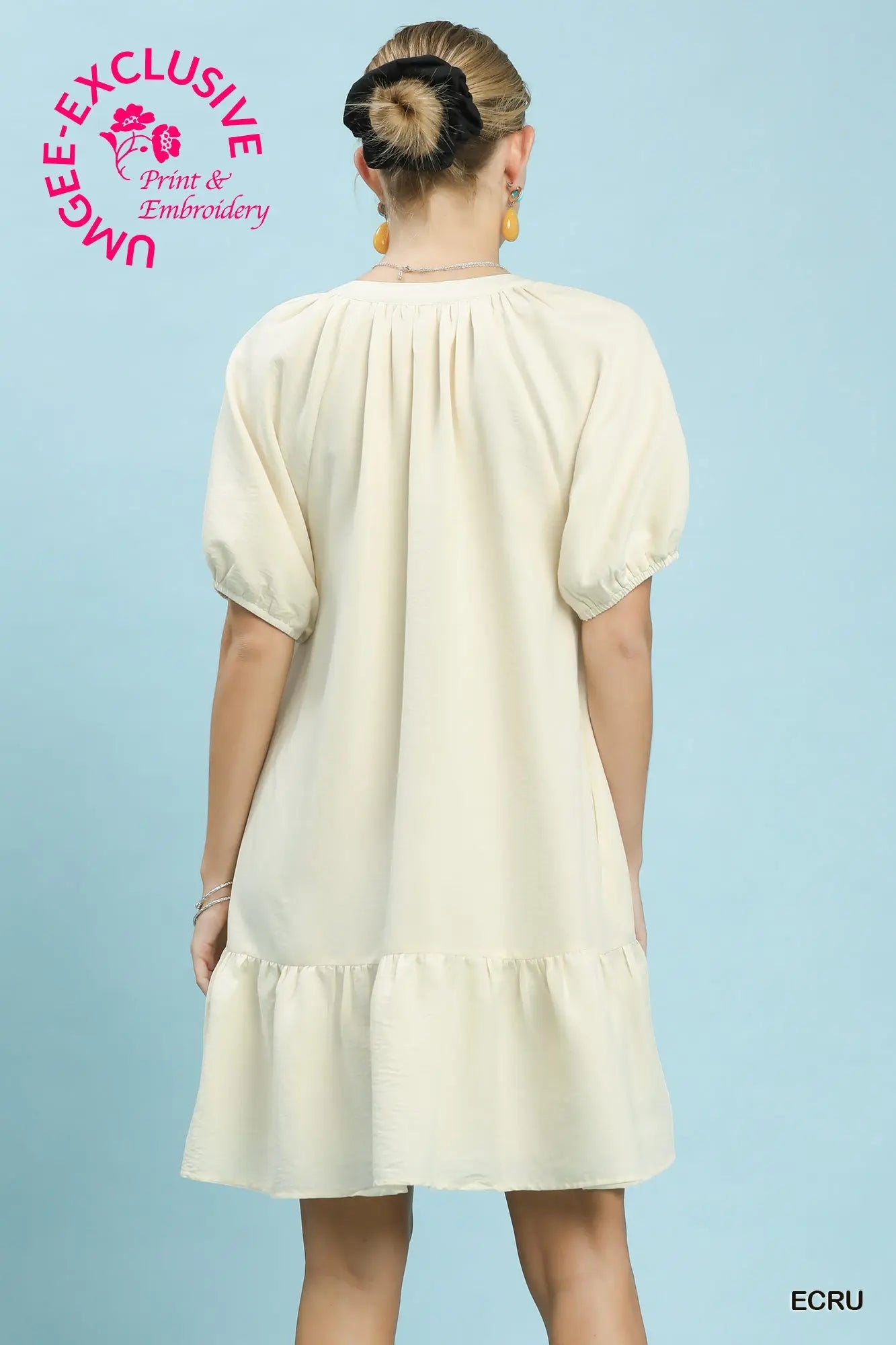 Woman wearing a cream dress with 'UMEE Exclusive' branding on a light blue background
