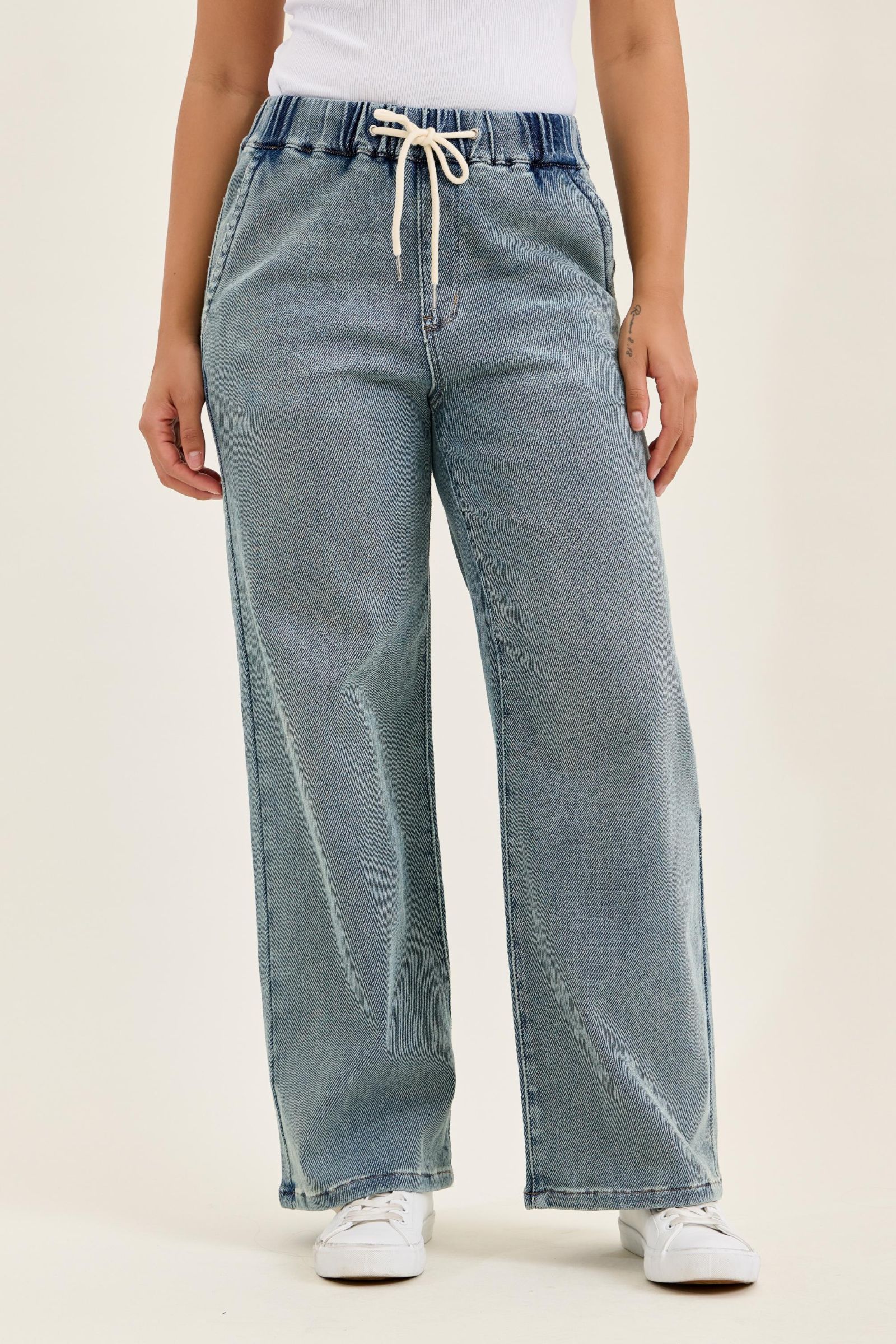 Light blue jeans with a drawstring waist on a plain background