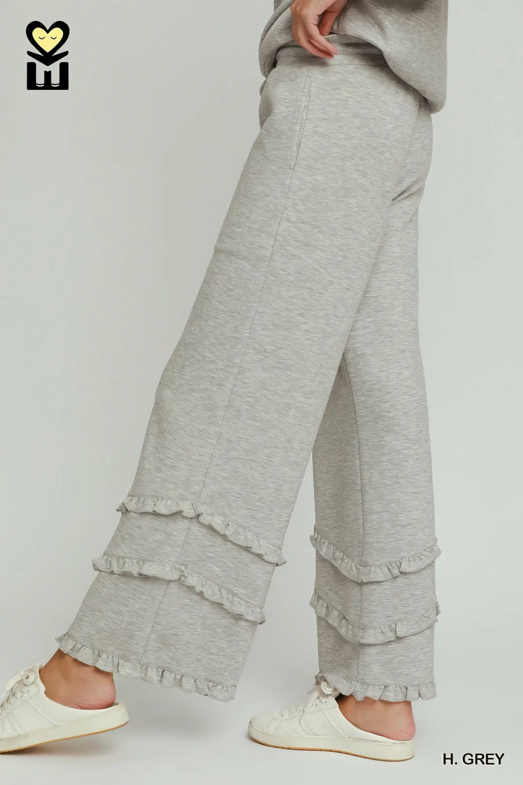 Gray ruffled pants worn by a person on a white background