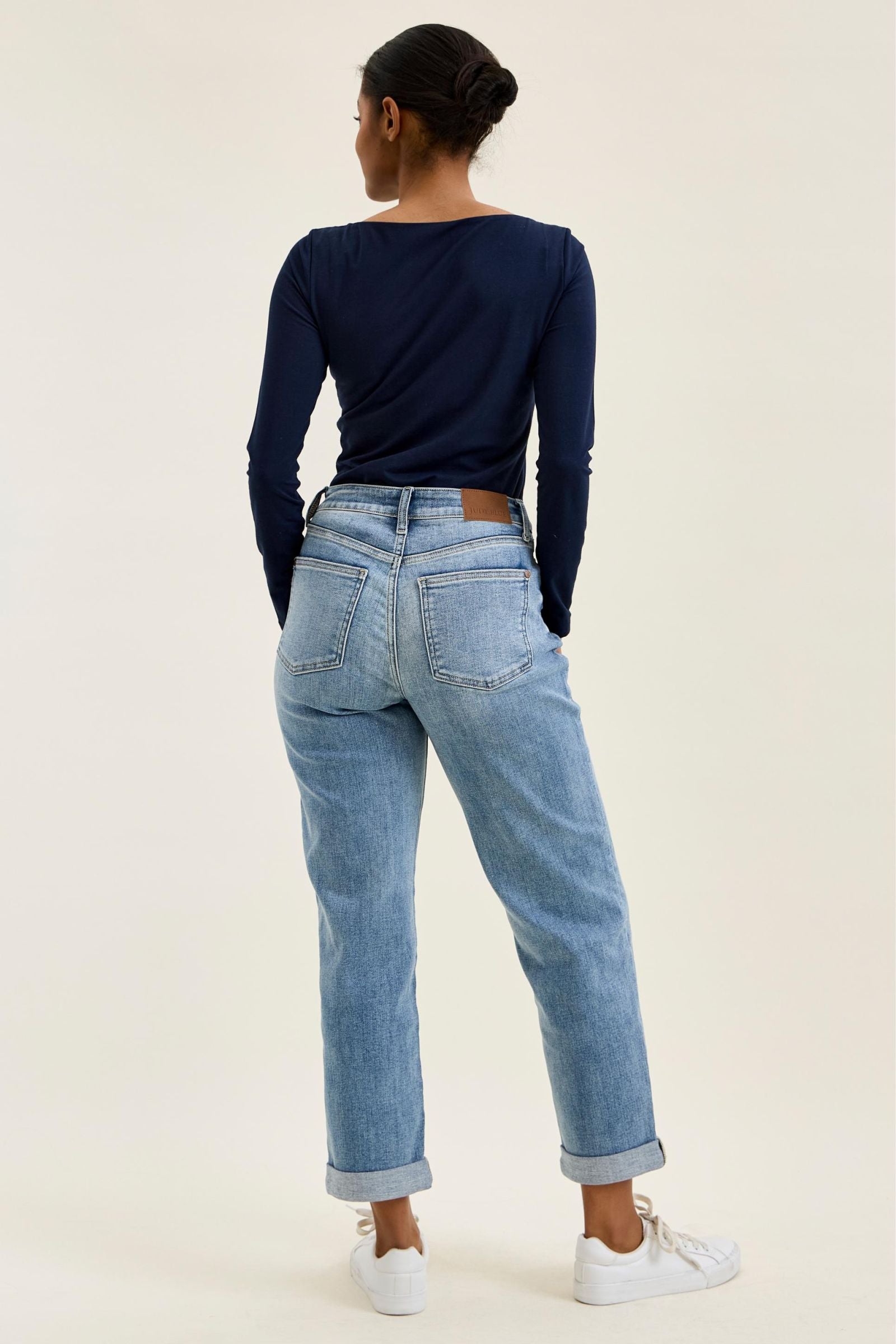 Person wearing blue jeans and a dark long-sleeve shirt on a plain background