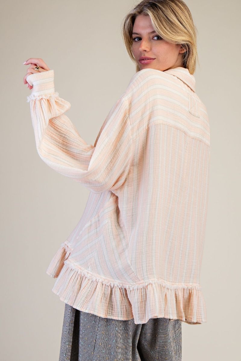 Woman wearing a beige and white striped blouse with ruffled details on a plain background