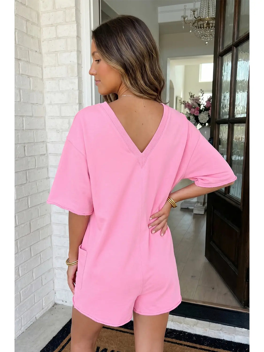 Woman wearing a pink romper in a home setting