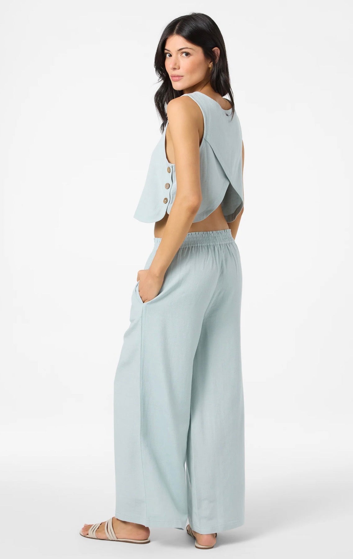 Woman wearing a light blue sleeveless top and wide-leg pants on a white background
