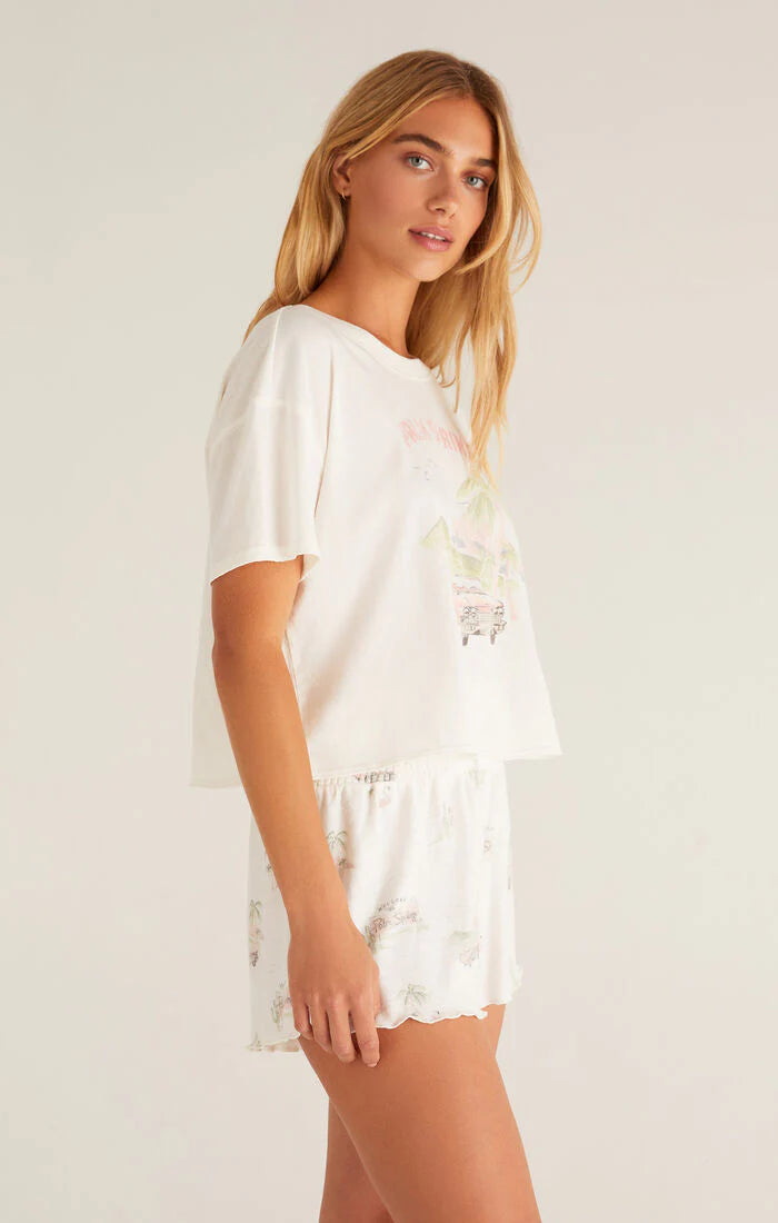 Woman wearing a white pajama set with lace details on a plain background