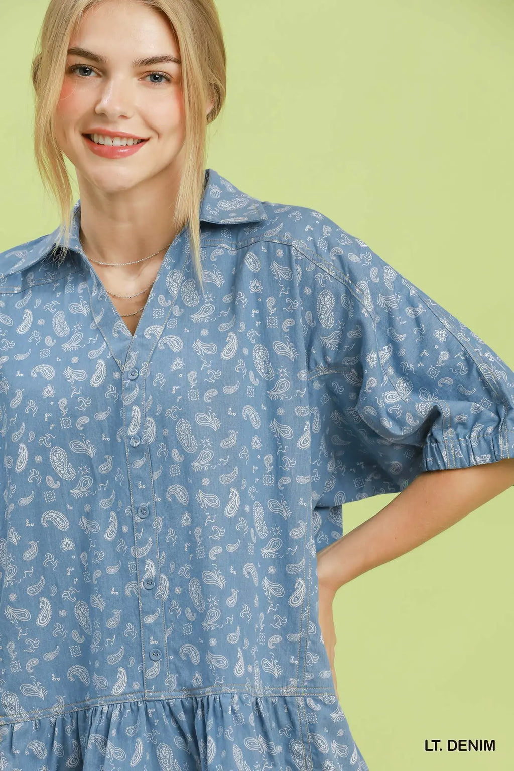 Woman wearing a light denim dress with a subtle pattern on a green background