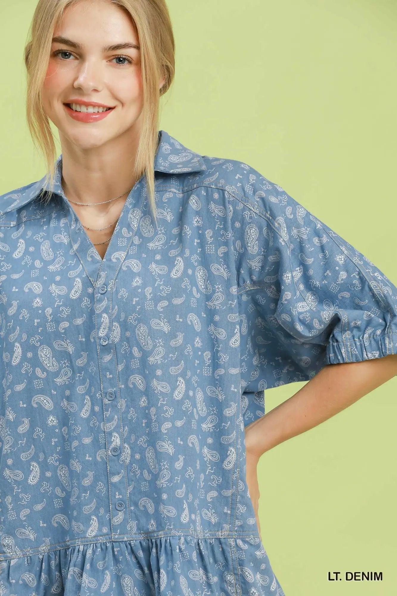 Woman wearing a light denim dress with a subtle pattern on a green background