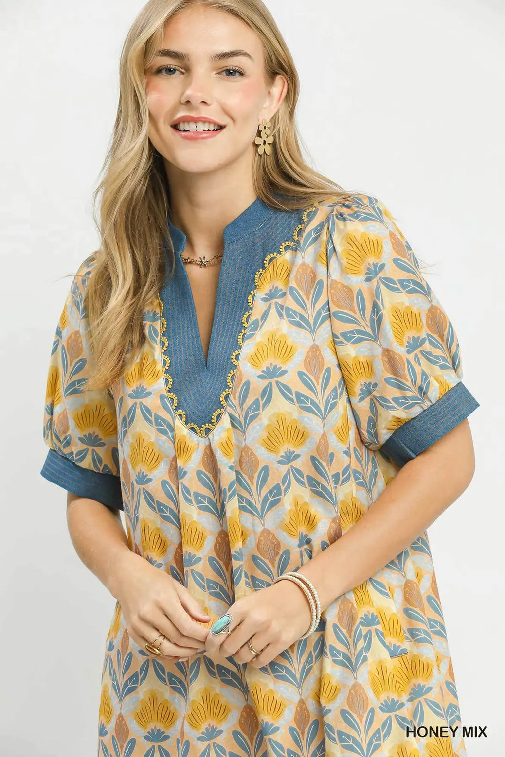 Woman wearing a patterned dress with blue neckline on a white background