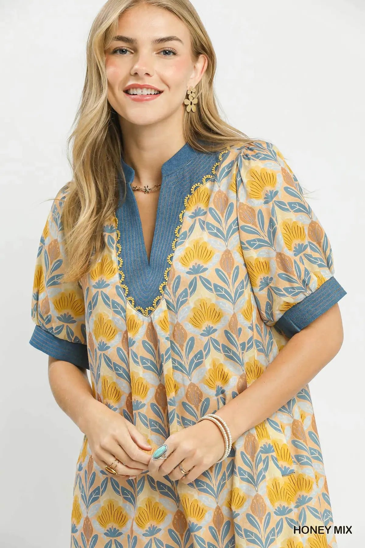 Woman wearing a patterned dress with blue neckline on a white background