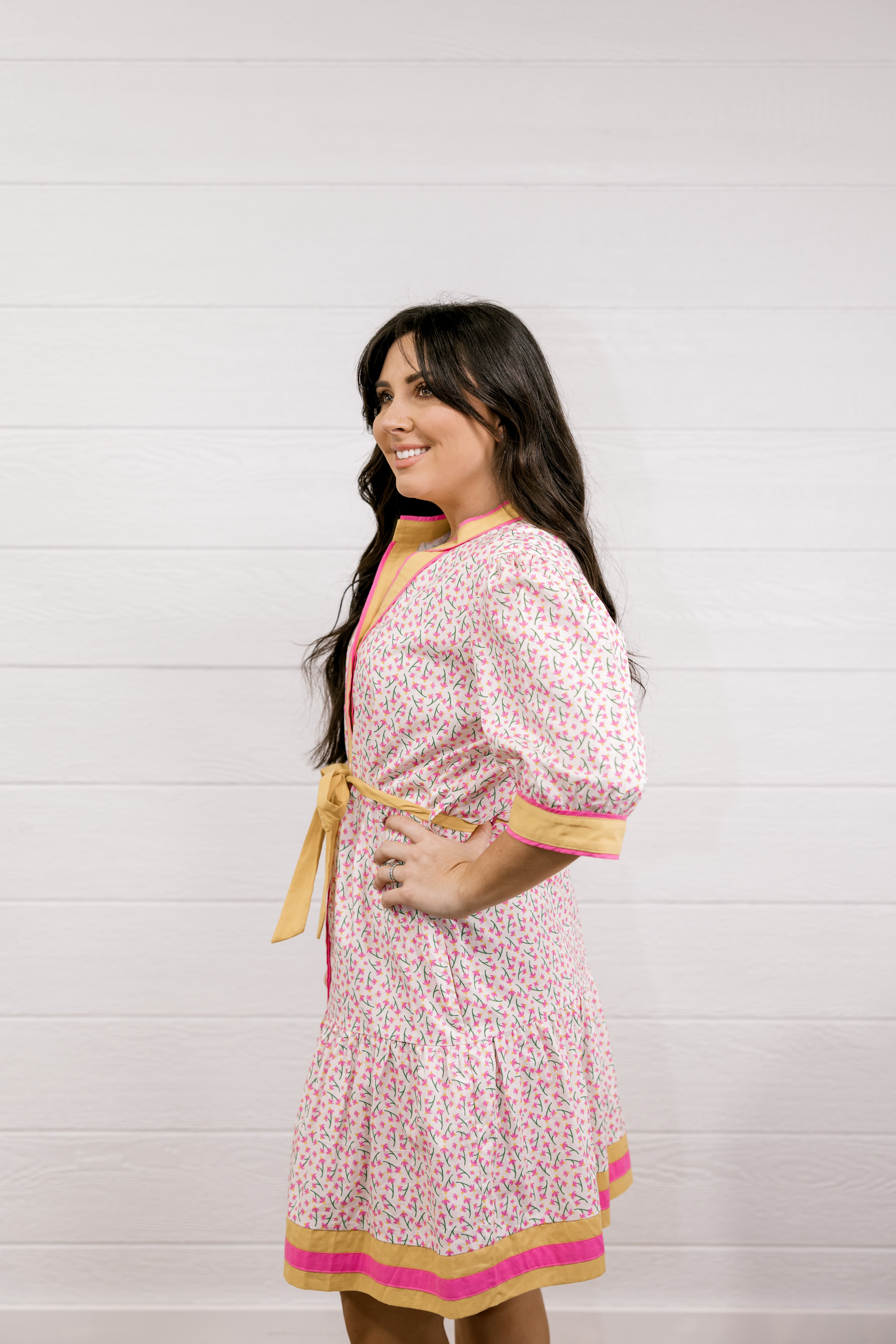 Woman wearing a pink floral dress with yellow accents against a white background