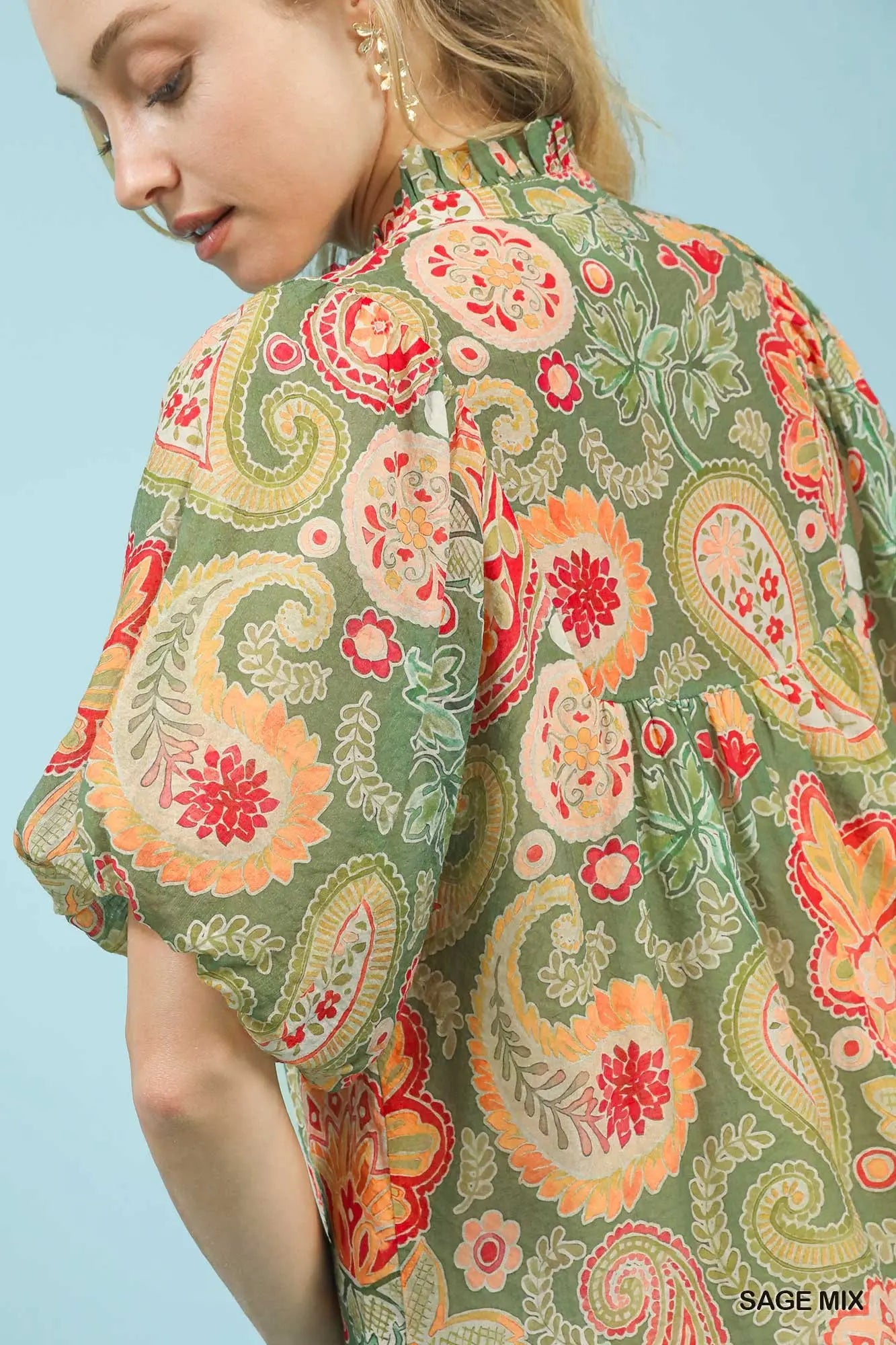 Woman wearing a floral patterned top against a light blue background