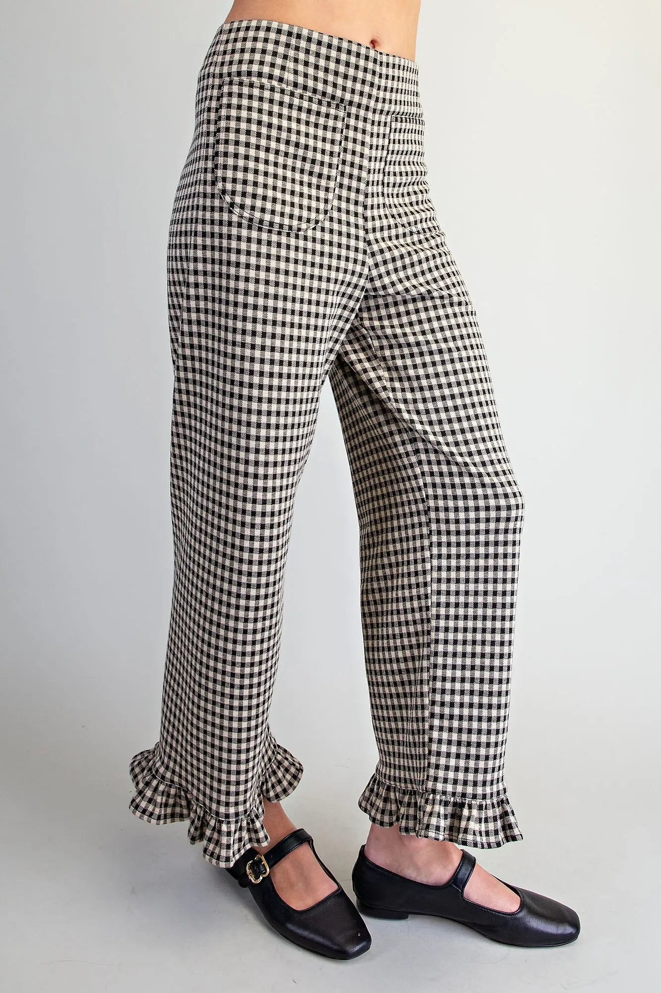Black and white gingham wide-leg pants with ruffled hems, shown on a model wearing black Mary Jane shoes against a light gray background.