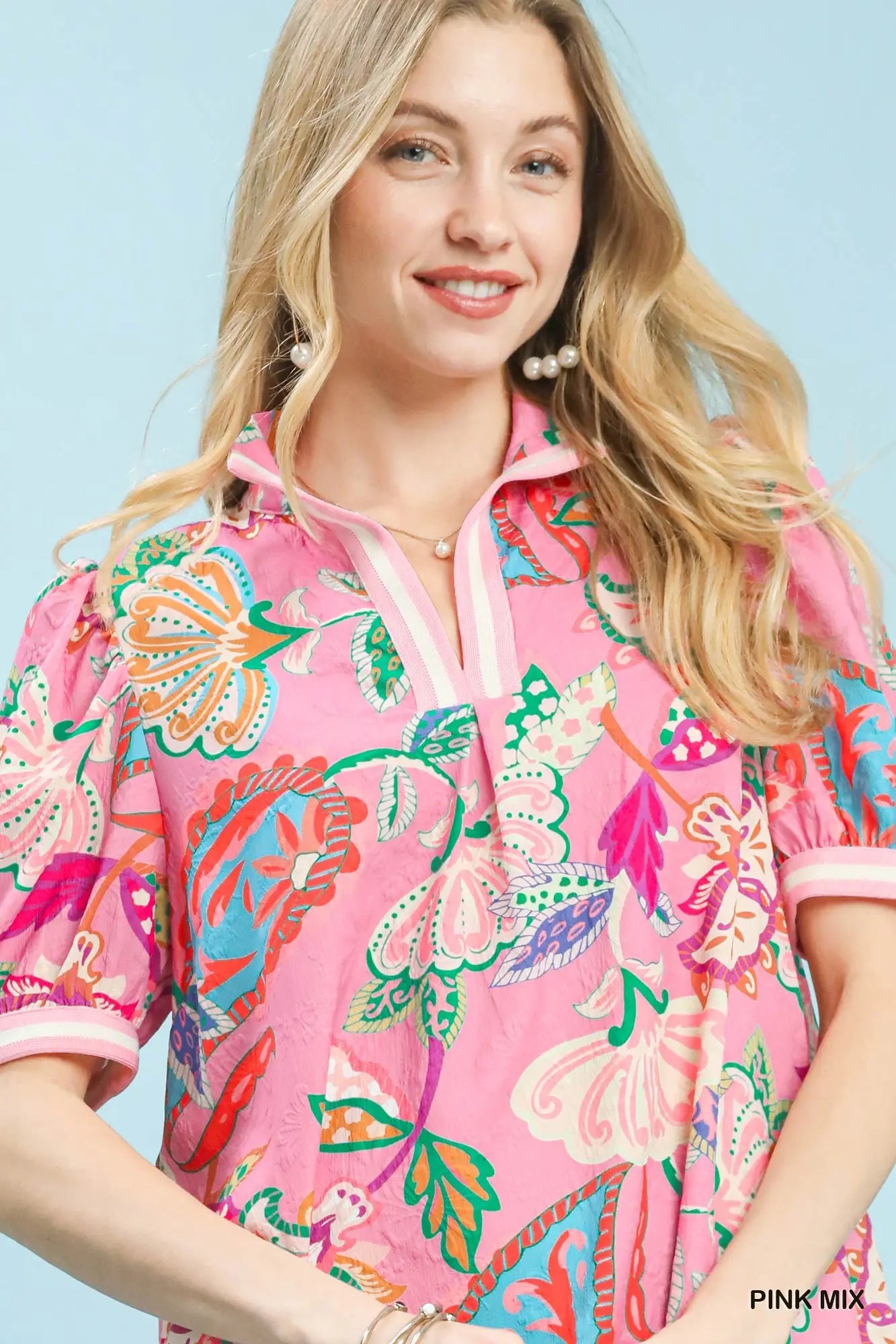 Woman wearing a colorful floral patterned shirt against a light blue background