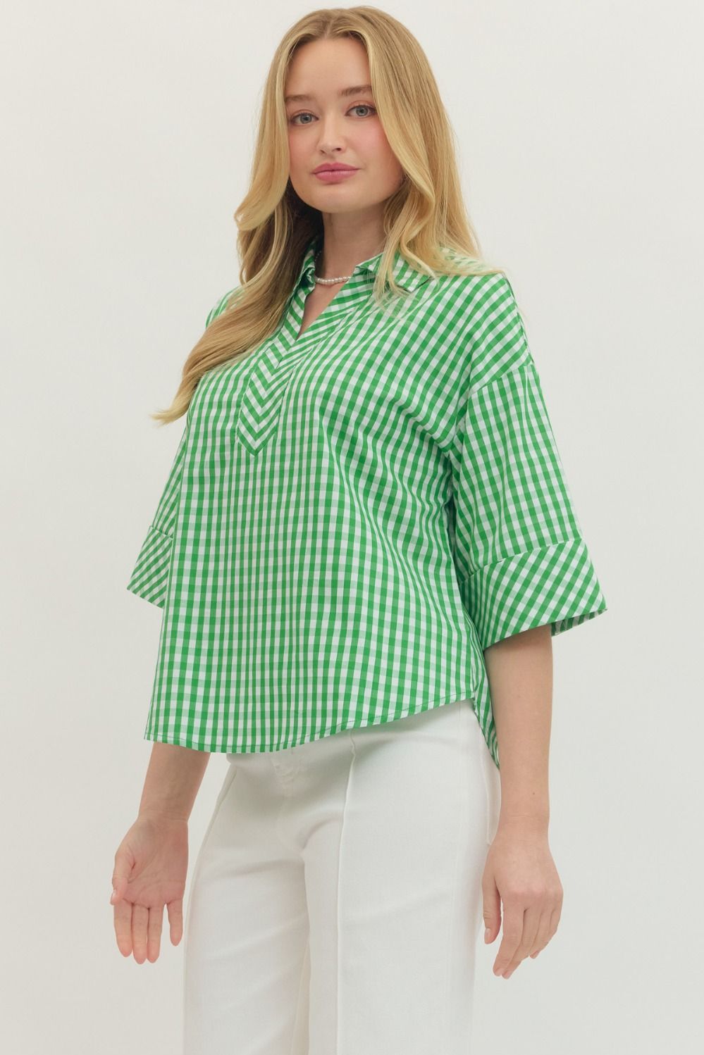 Woman wearing a green and white checkered blouse on a plain background