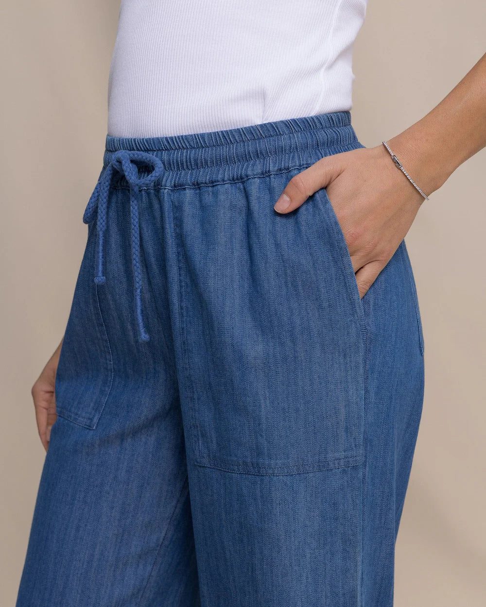 Person wearing blue denim pants with a beige background