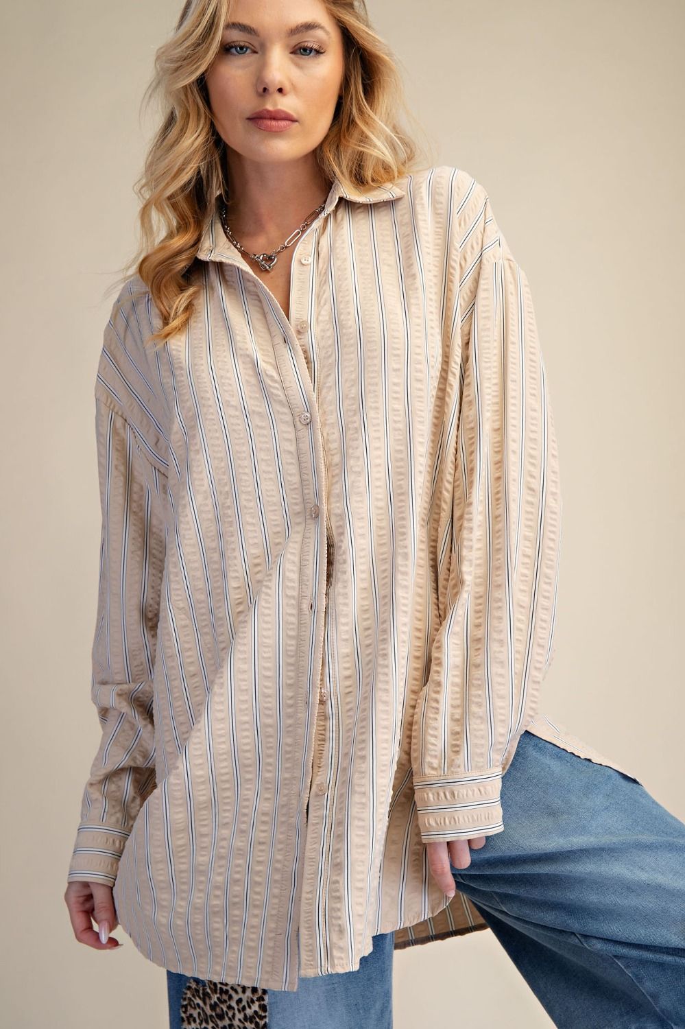 Woman wearing a long, striped shirt with a neutral background