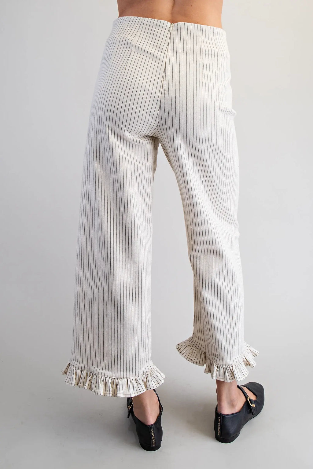 White ribbed pants with ruffle hem on a plain background